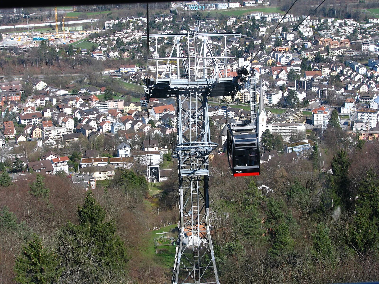 Une cabine du téléphérique Adliswil–Felsenegg passant un pylône, très haut au-dessus des maisons d’Adliswil