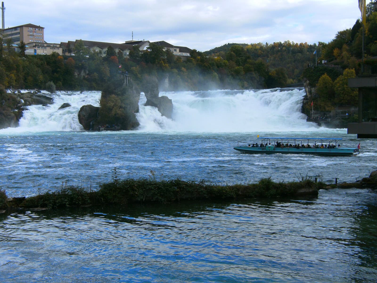Un bateau d’excursion devant les chutes du Rhin écumantes, avec le rocher au milieu du courant
