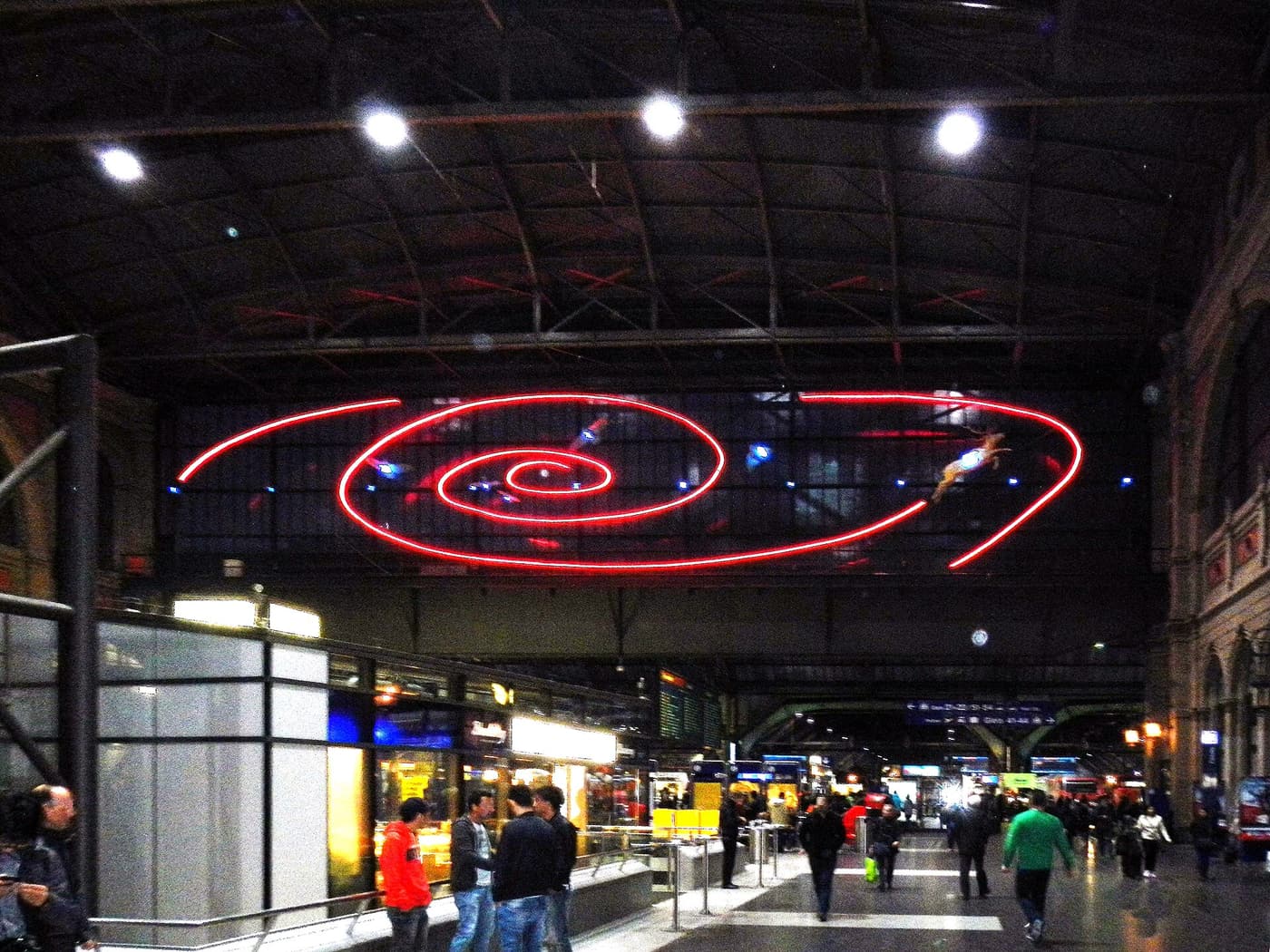 Le grand hall de la gare centrale de Zurich avec une spirale de néon rouge sous la verrière